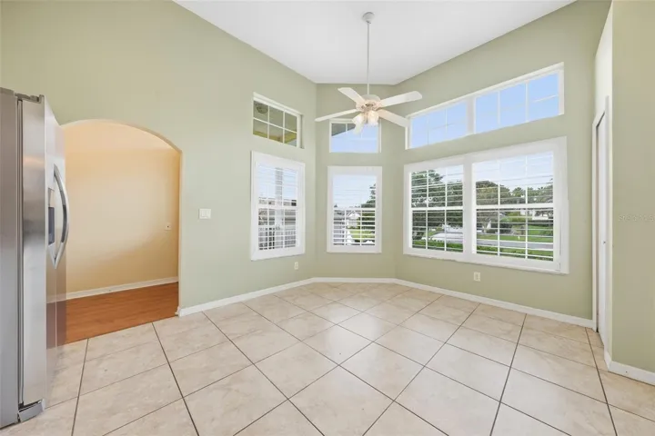 Sun-filled breakfast nook featuring valuted ceilings, expansive windows, and plantation shutters.
