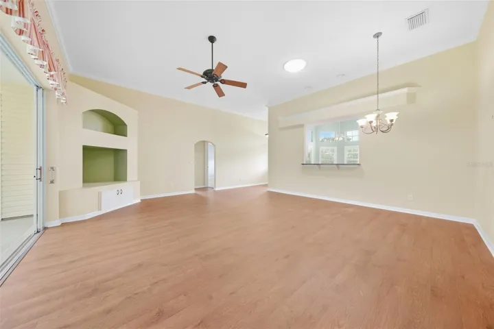 Spacious living area featuring a custome built-in entertainment center with architectural niches and warm wood flooring.