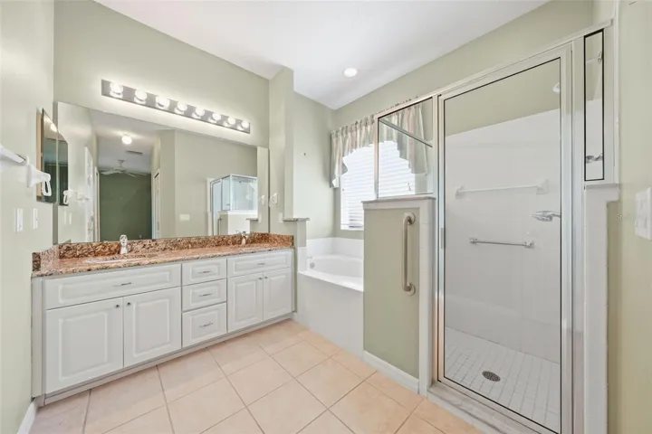 Spacious primary bath with granite vanity, soaking tub, and separate walk-in shower.
