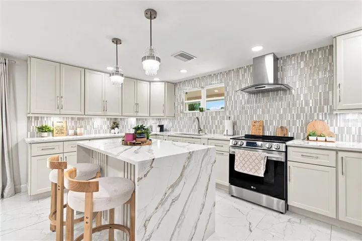 Quartz waterfall edge creates a visual stop in the kitchen area that works elegantly with upscale cabinetry, and backsplash.