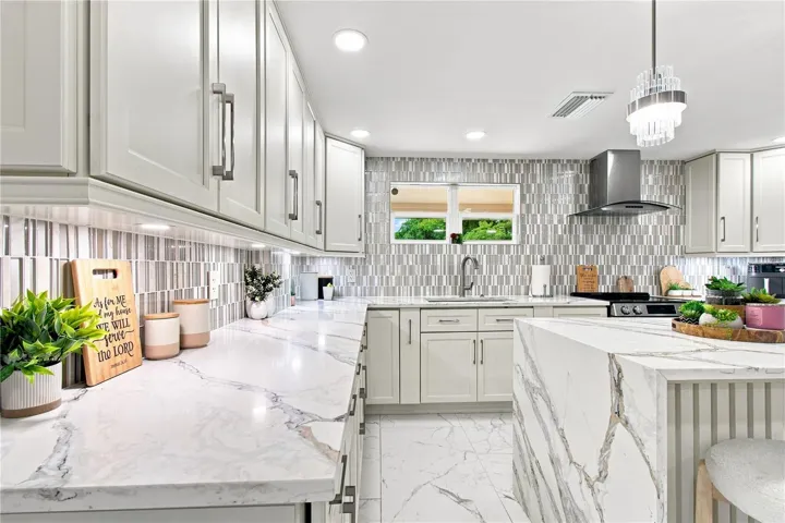 Quartz waterfall edge creates a visual stop in the kitchen area that works elegantly with upscale cabinetry, and backsplash.