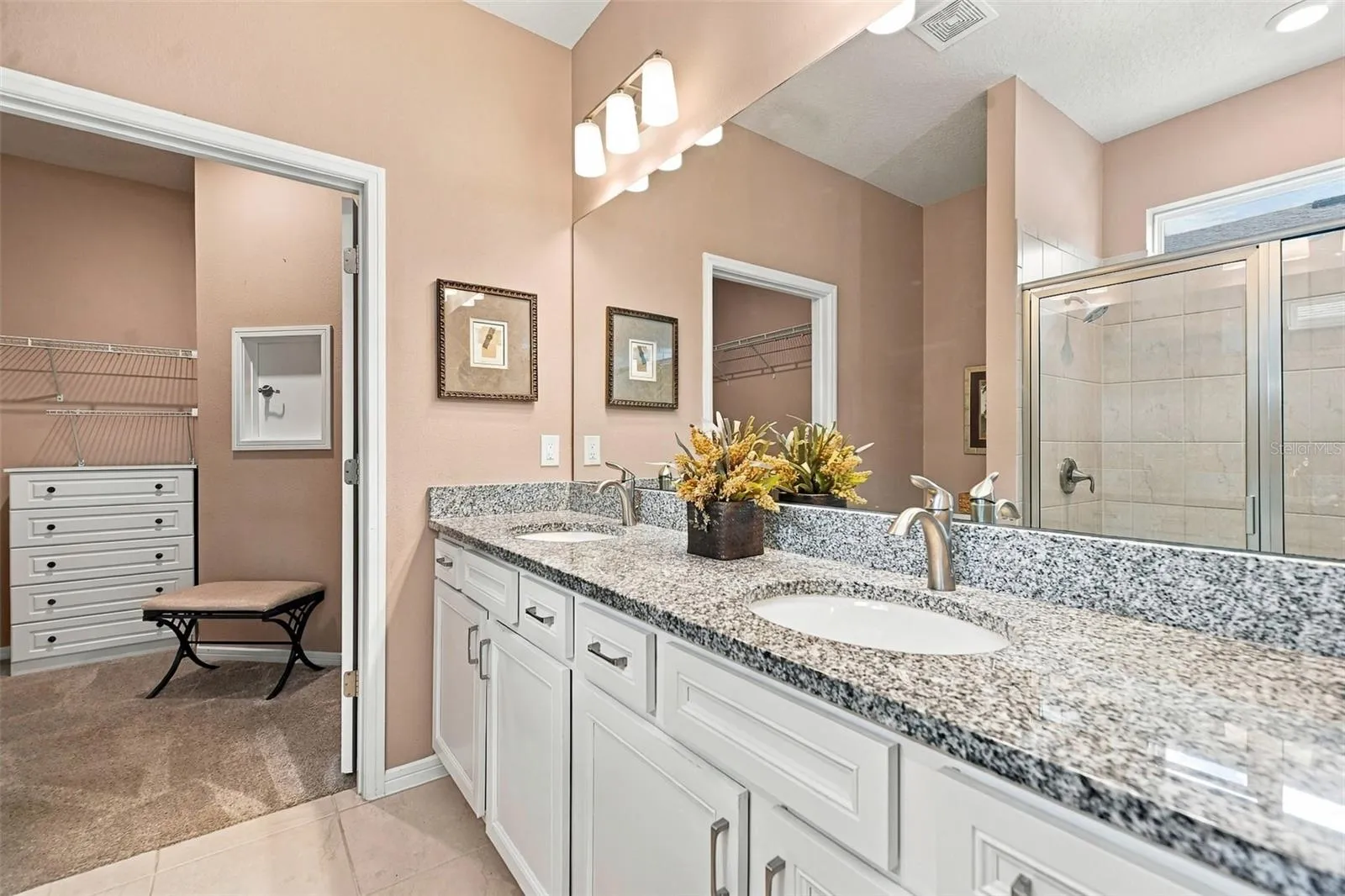 Primary en-suite bath w/walk-in tiled shower, built-in bench, transom window, granite countertop, dual vanity &amp; closet w/laundry chute door