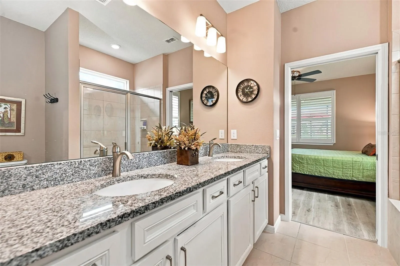 Primary en-suite bath w/walk-in tiled shower, built-in bench, transom window, granite countertop, dual vanity &amp; closet w/laundry chute door