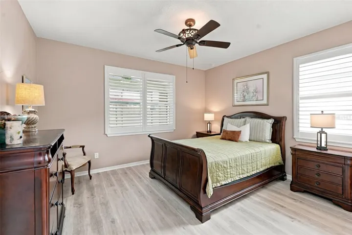 Primary Bdrm w/luxury vinyl plank floors, ceiling fan, &amp; windows w/plantation shutters