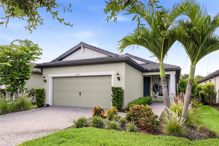 Front of Home showcasing the lush landscaping and the coastal elevation with cool tones.