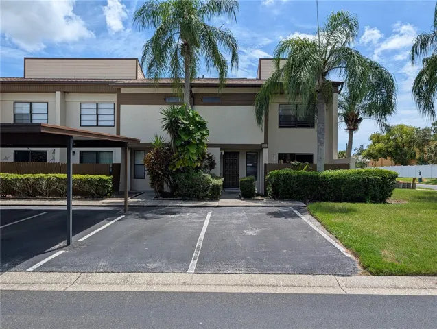 Front exterior of corner unit with covered assigned parking and guest parking