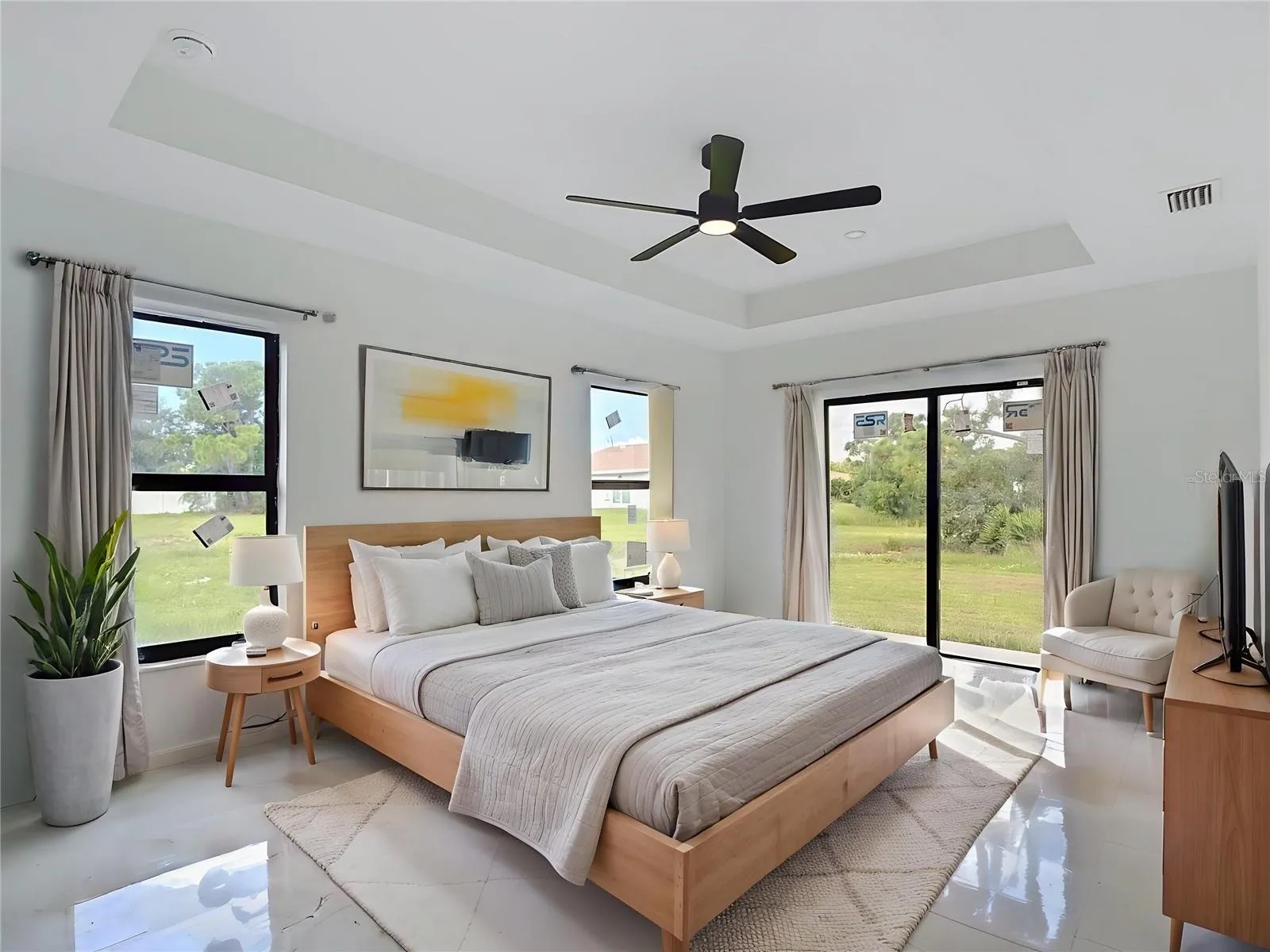 Staged primary bedroom with sliders onto the backyard.