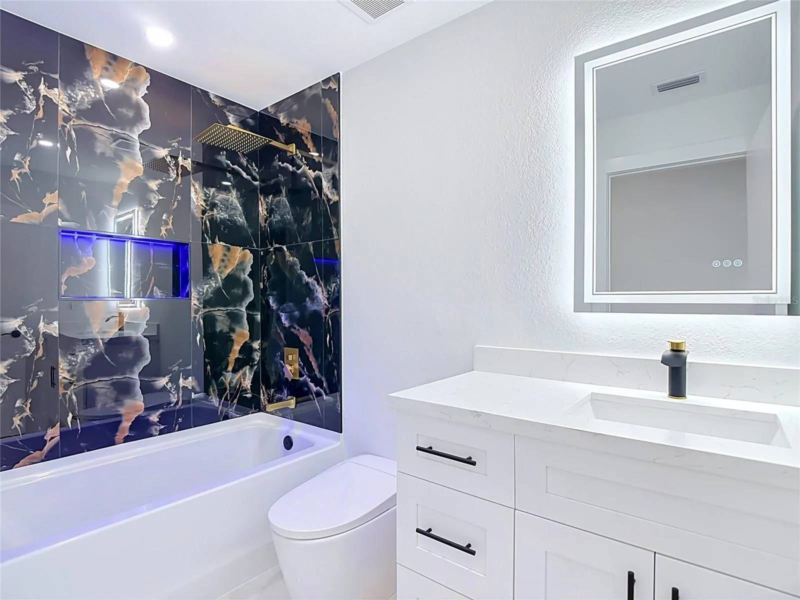 2nd bathroom features bathtub with lit cubby, smart mirror, toilet with bidet and a single vanity.