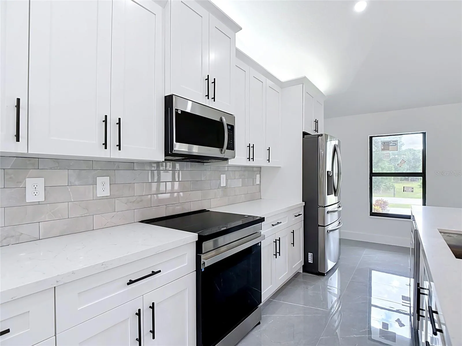 Gourmet kitchen features lighting above cabinets, quartz countertops, stainless steel appliances including an induction oven, microwave, dishwasher & refrigerator!