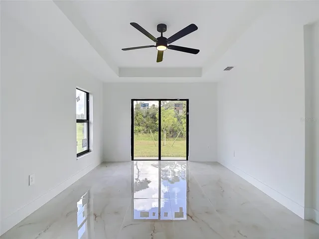 Primary bedroom with tray ceiling, ensuite bathroom, walk in closet and sliding doors to backyard