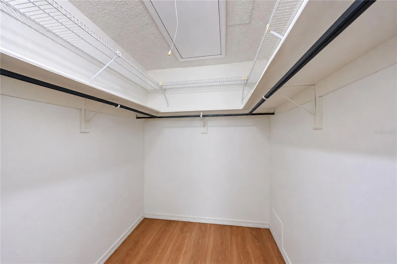 Primary bedroom walk-in closet with pull down stairs to attic