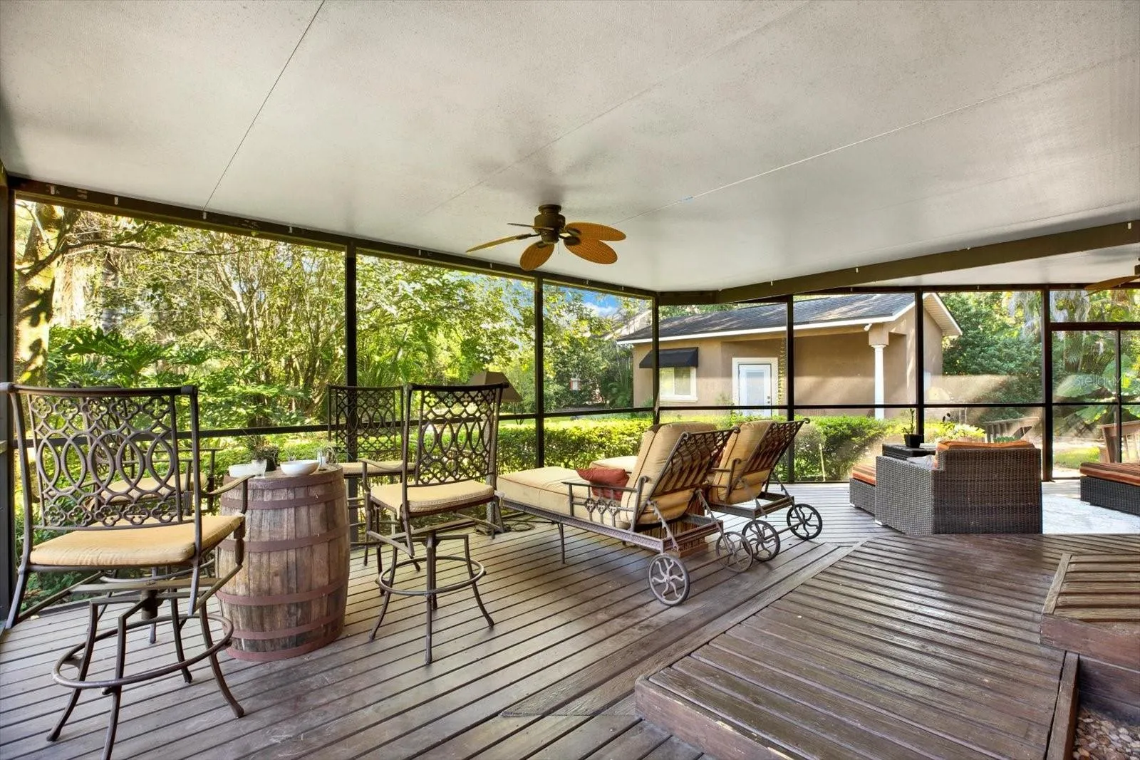 Screened lanai with a wood deck and seating area.