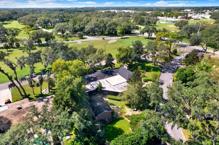 Aerial view highlighting the golf course green and mature tree canopy surrounding the property.