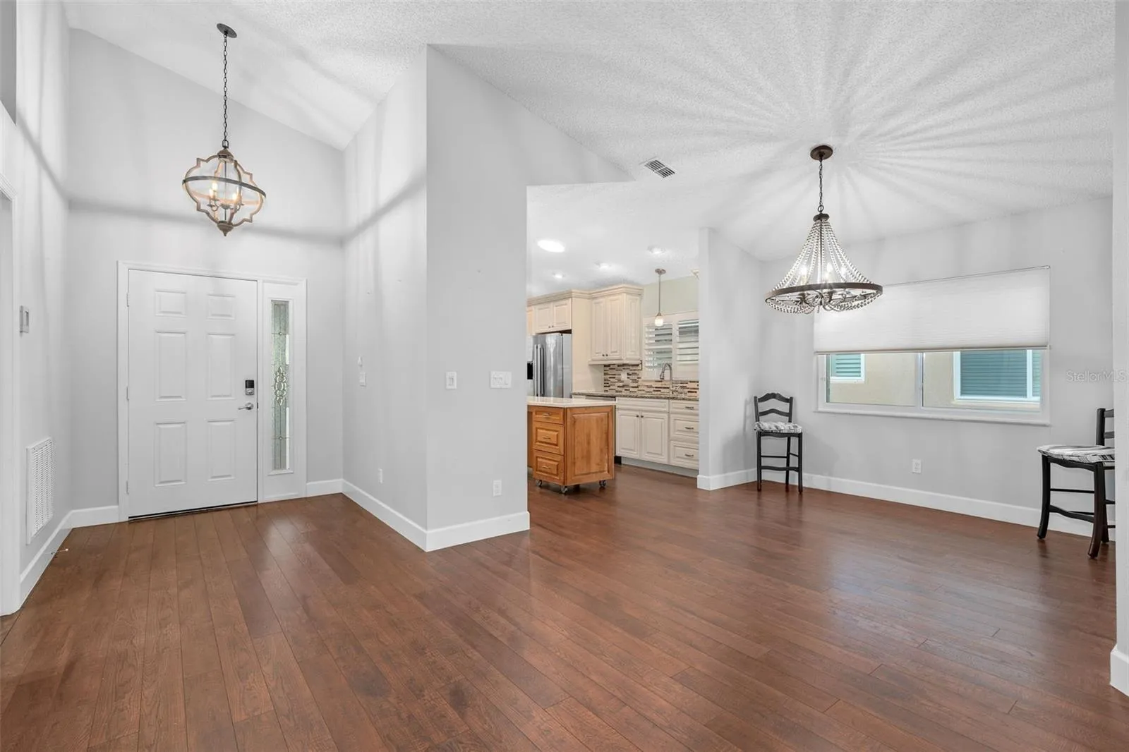 entry way into the home showing the kitchen and dining area. Home has upgraded light fixtures and luxury laminate flooring.