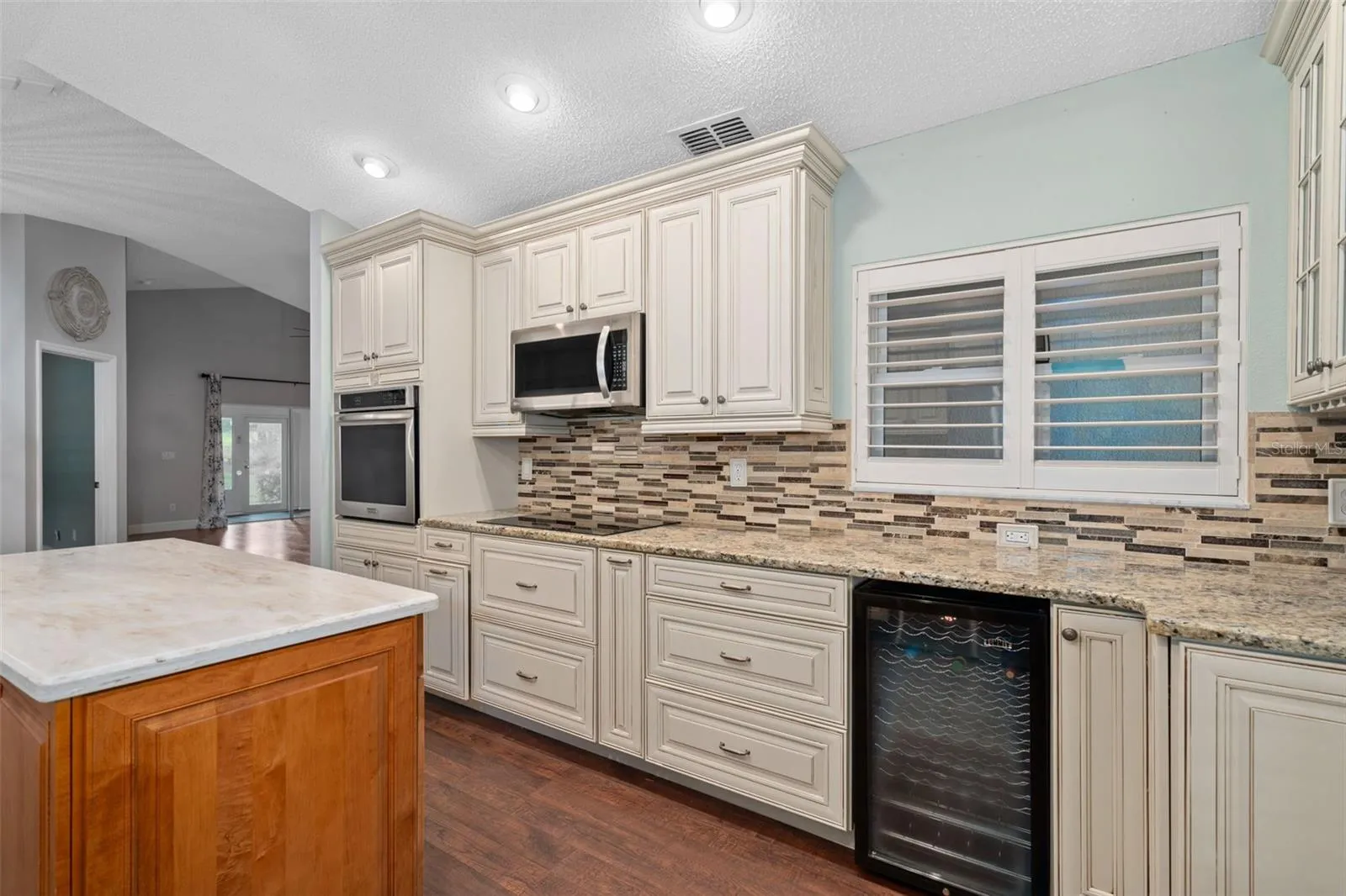 view of the custom cabinetry and wine fridge. Middle island is moveable to make it easier to place it where you need it the most.