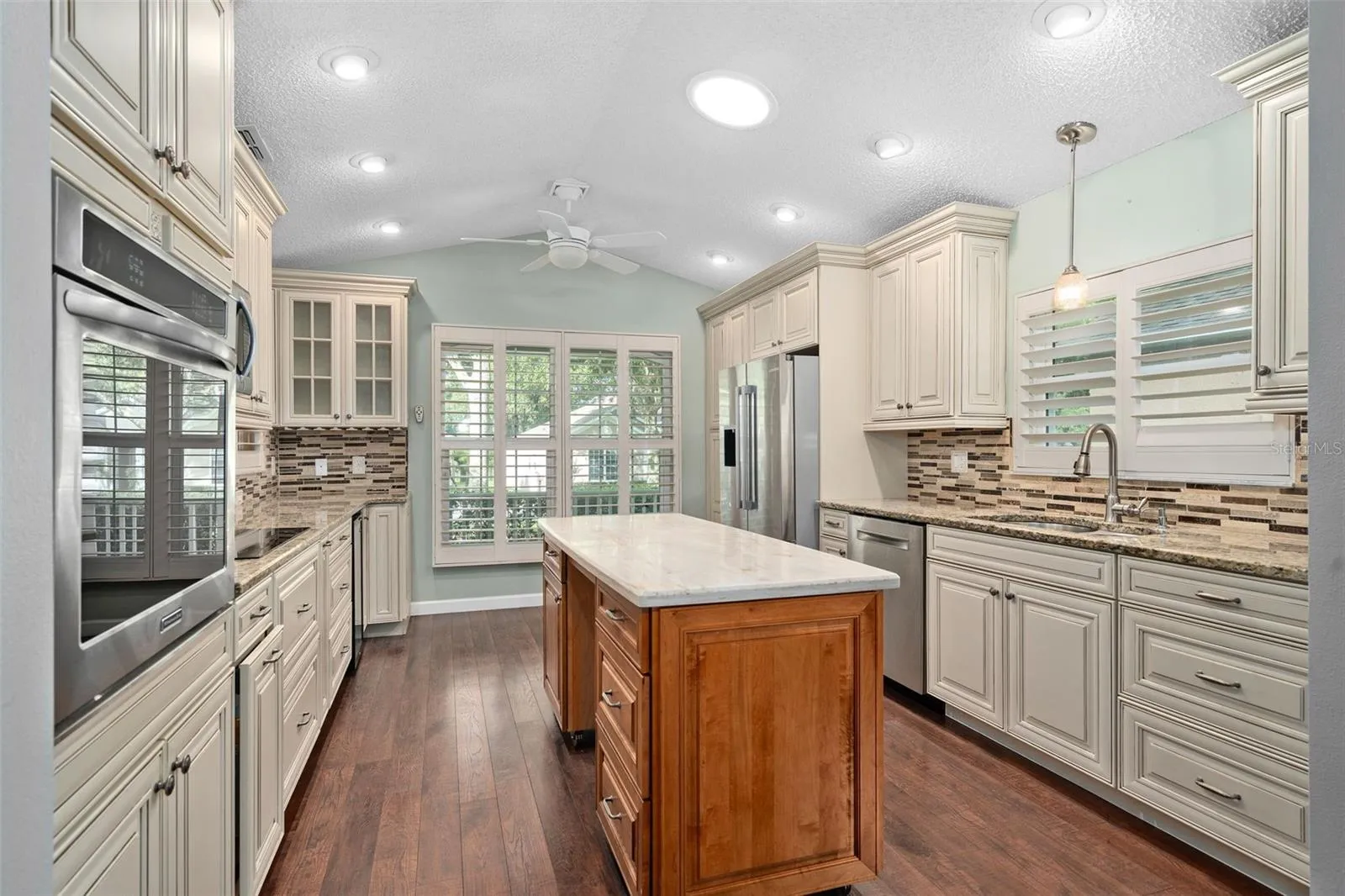 beautiful custom antiqued kitchen cabinets with granite countertops and a custom backsplash. Also has stainless steel appliances,plantation shutters, and a wine refrigerator.