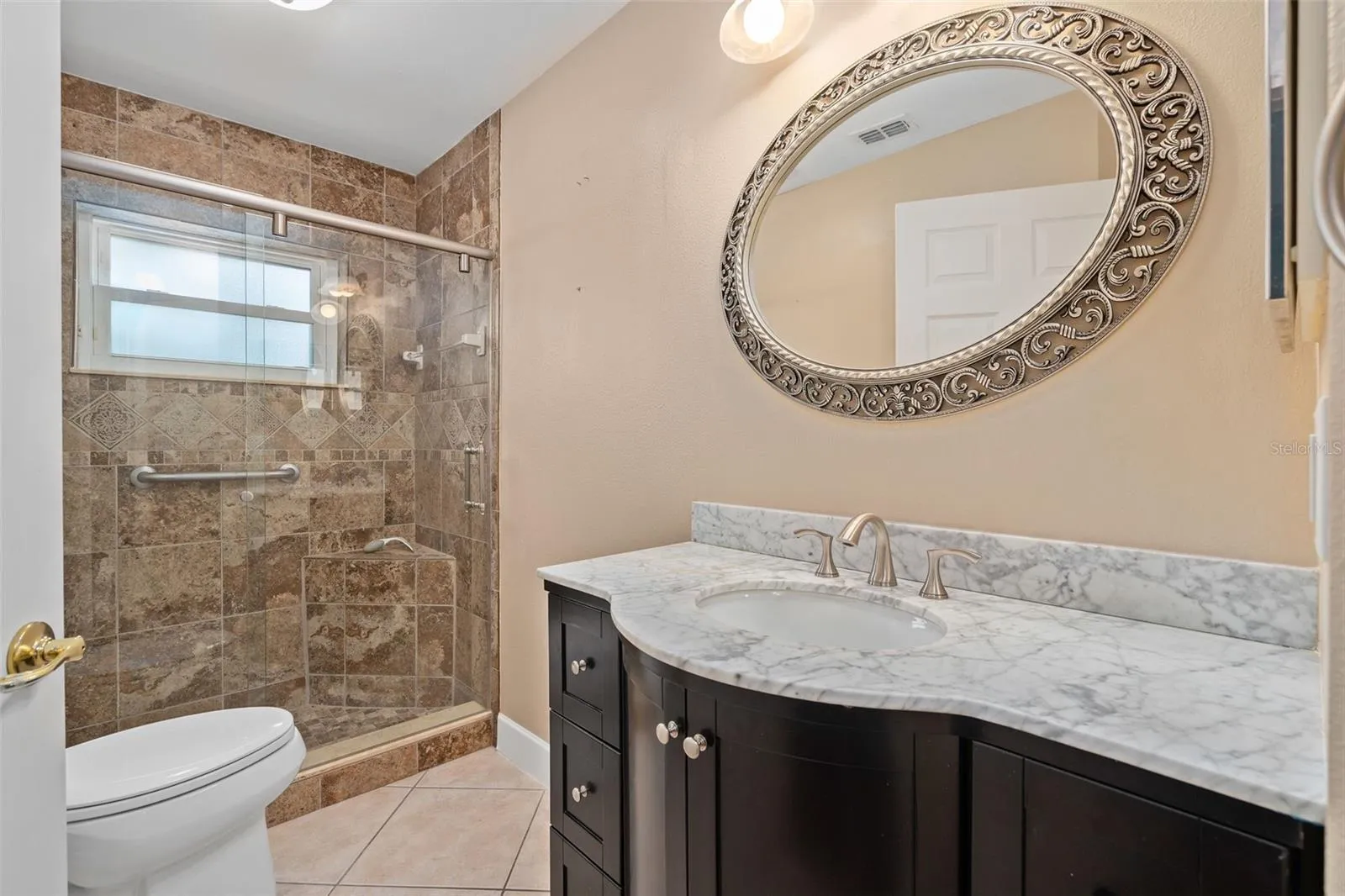 Bathroom 2- beautifully remodeled with a custom vanity and upgraded tile in the shower and floor with a frameless shower door.