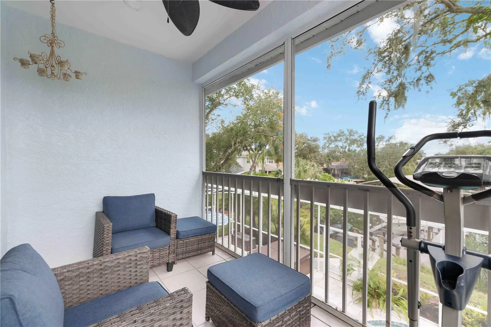 A private screened balcony off the upstairs suite, with treetop views and comfortable seating for morning coffee.
