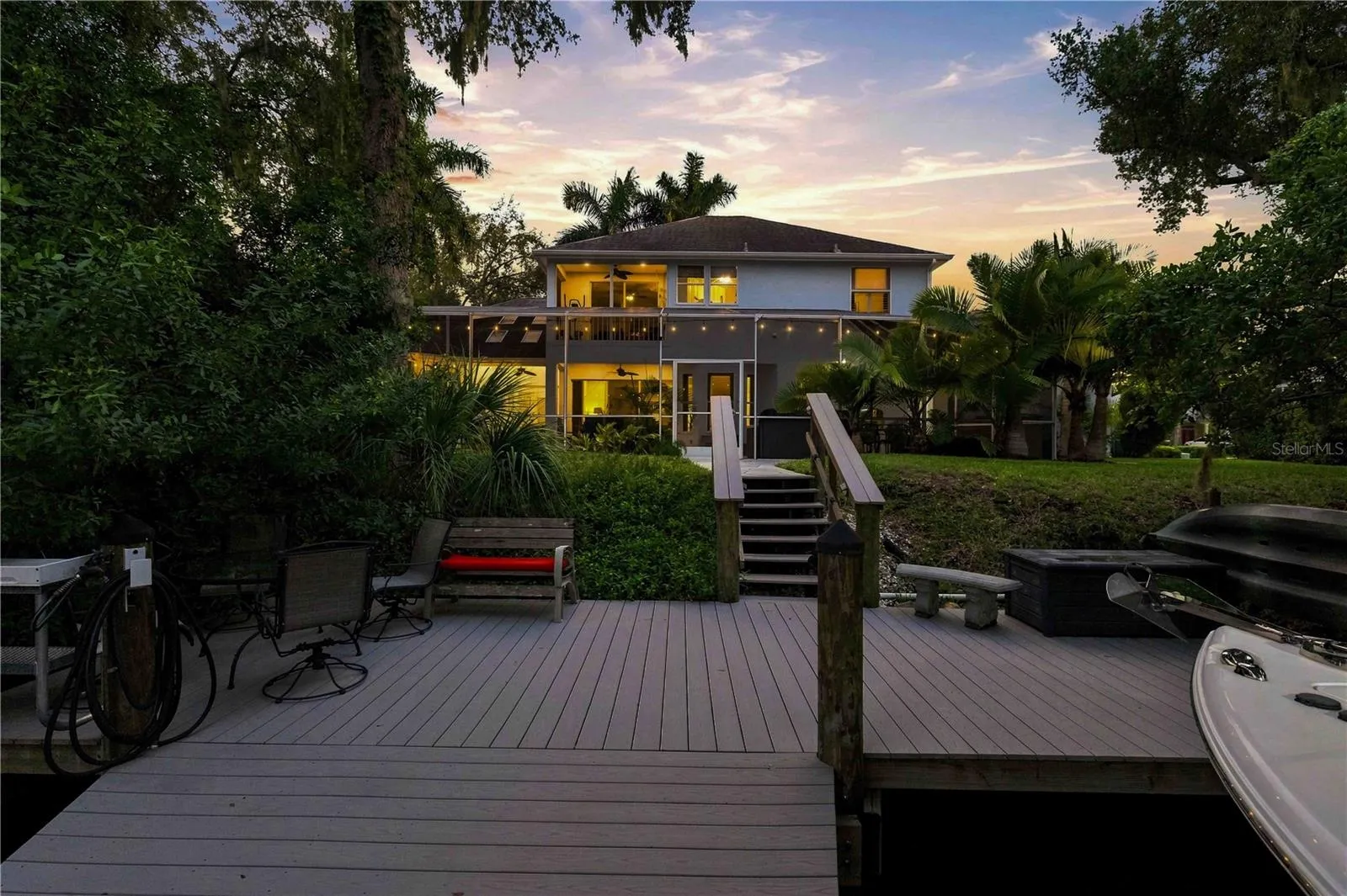 A spacious rear deck with seating leads down to the water — the natural gathering spot for sunset views