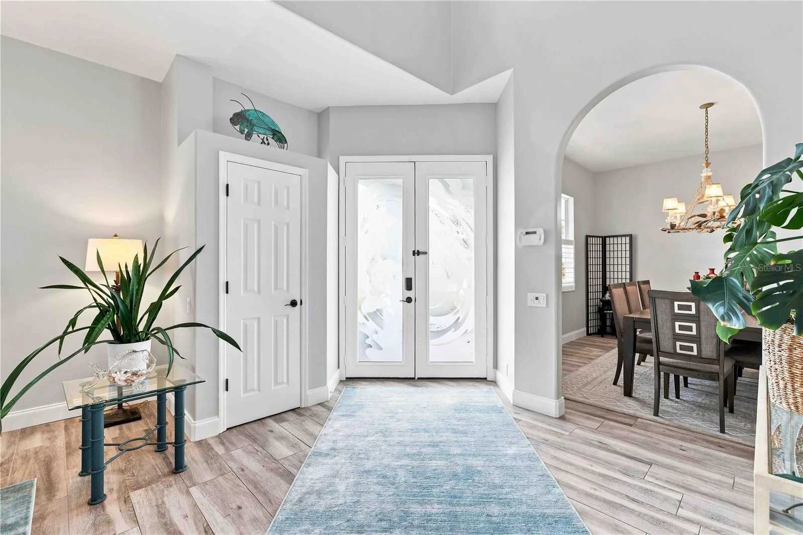 The artist-commissioned glass entry doors are even more stunning from inside, framed by soaring ceilings and an open flow into the dining room