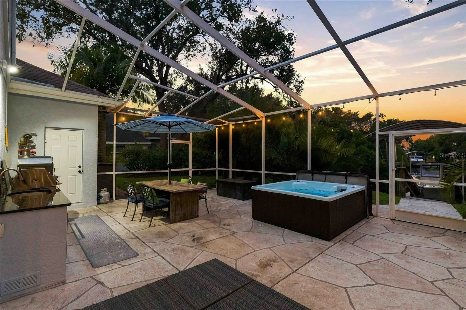 A magical dusk shot of the lanai — string lights, an open-air hot tub, and an outdoor kitchen come together for the ultimate Florida evening