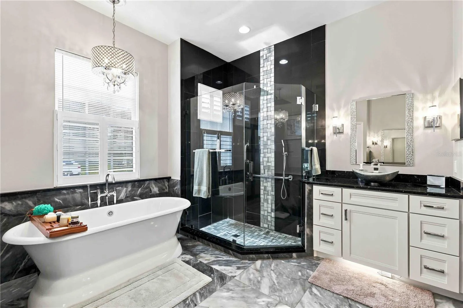 A spa-like primary bath with a floor-to-ceiling glass shower, dual rainhead, and a freestanding soaking tub.