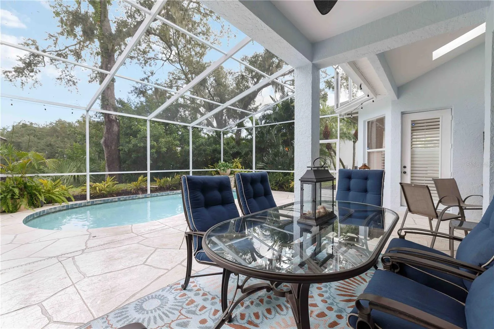 Covered lanai seating overlooks the pool and lush landscaping — an easy spot for al fresco meals.