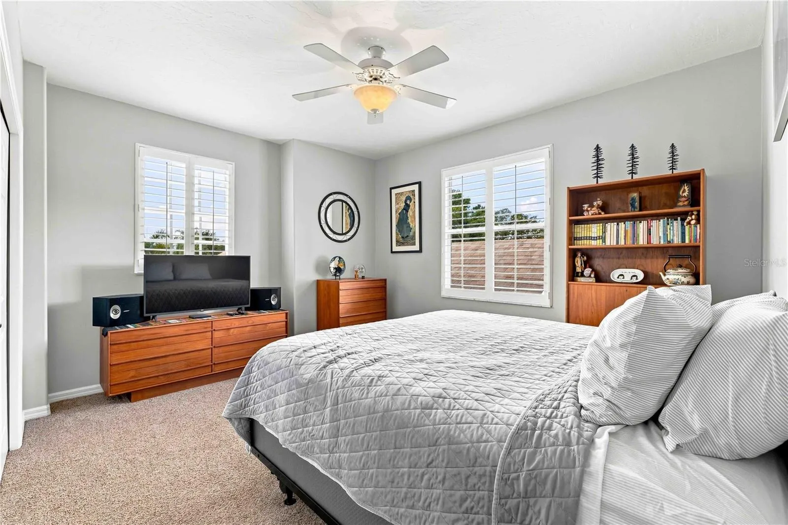 A warm, inviting guest bedroom with rich wood furnishings and a built-in bookshelf — comfortable for visiting family or friends
