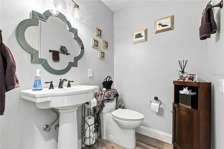 A charming first floor powder bath with a pedestal sink and ornate mirror — a lovely touch for guests