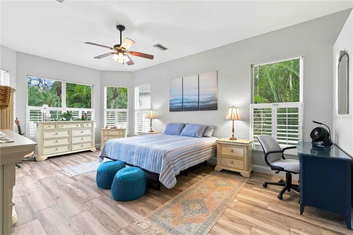 A spacious primary retreat with an electric fireplace, mounted TV, and plenty of natural light.