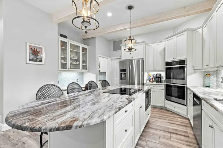 A dramatic waterfall-edge granite island anchors the kitchen, with double ovens and stainless appliances just steps away
