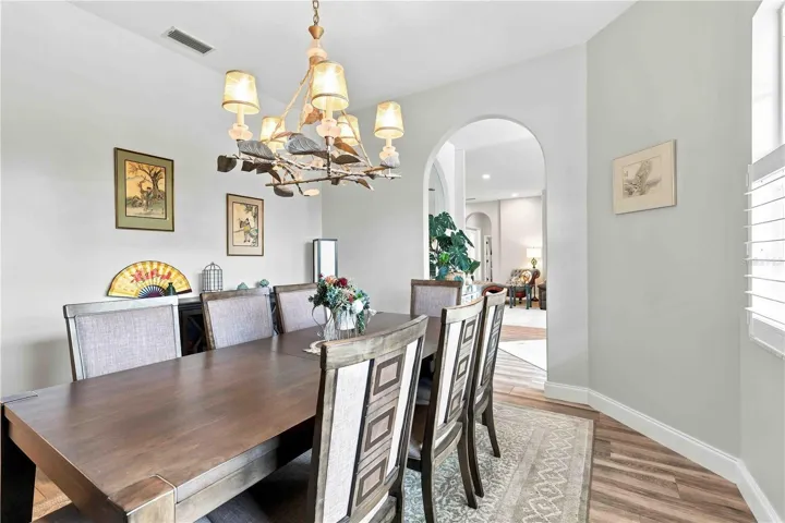 The dining room flows easily into the living space beyond, anchored by a statement chandelier and gallery-style art