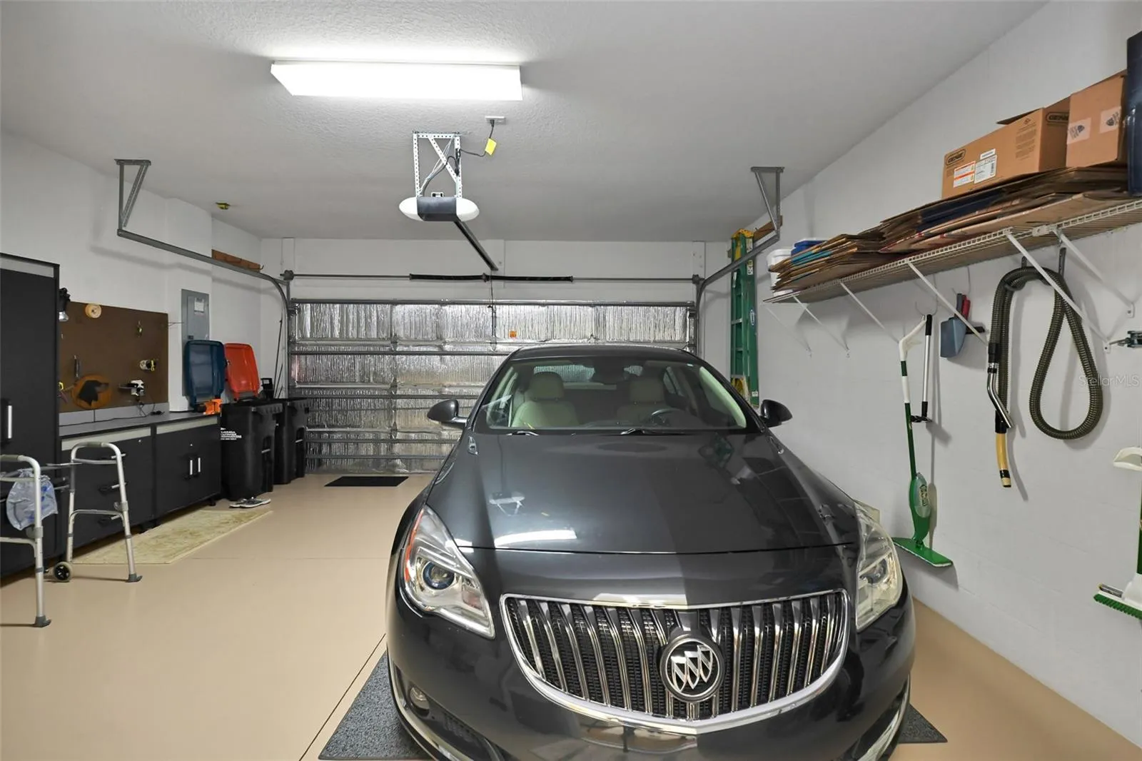 2 car garage with epoxy floor, insulated garage door, full screen, workbench, cabinets, garage door opener, water softener, water heater & installed storage racks