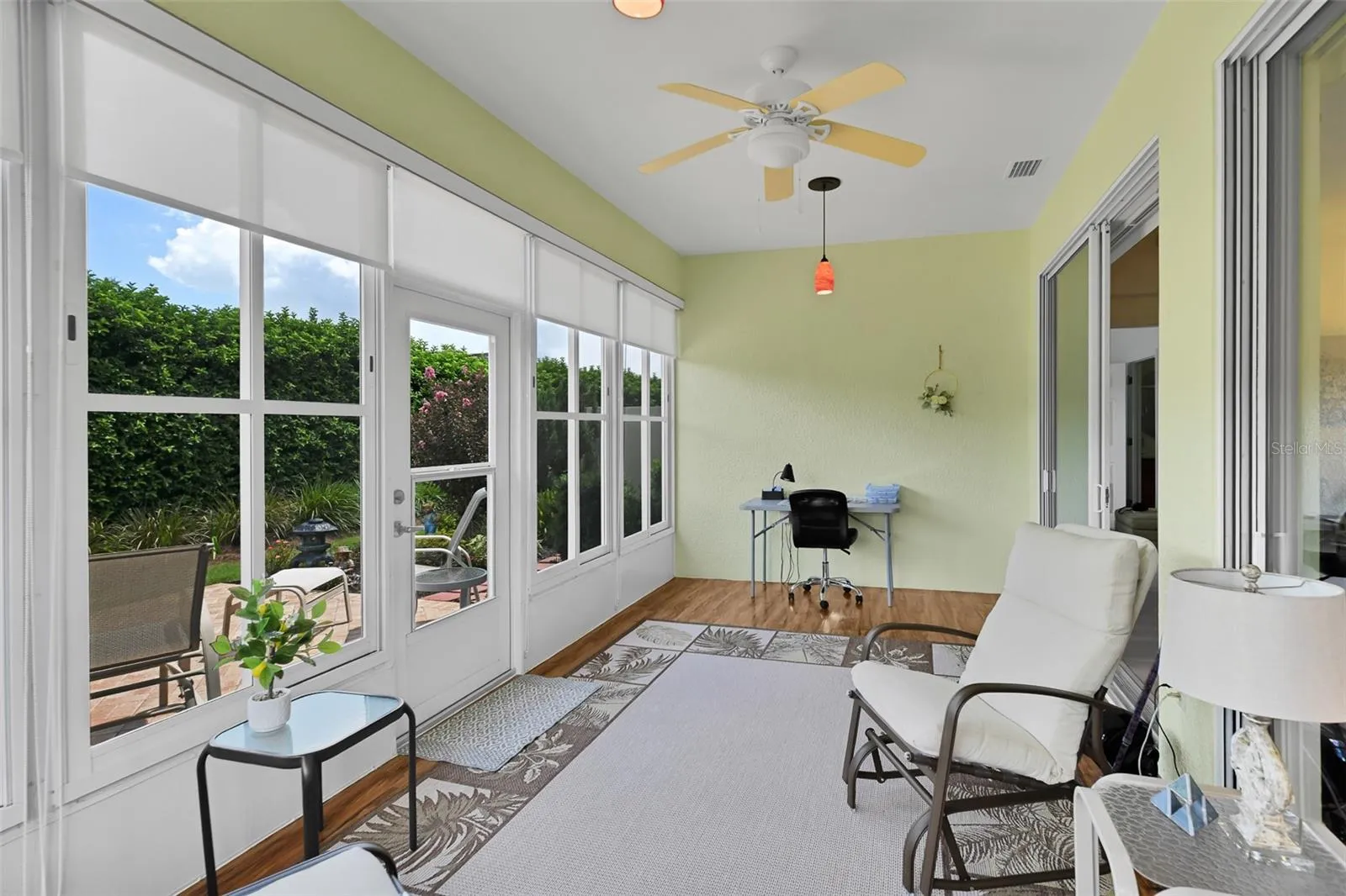 Enclosed lanai with shades, plank flooring, ceiling fan & pendant lighting