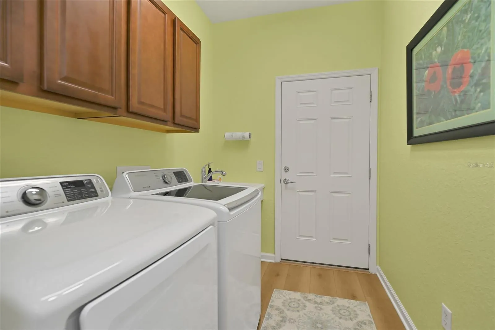 Laundry room with washer, dryer, cabinets, and utility sink