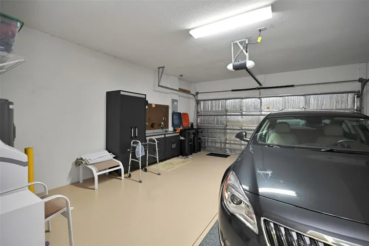 2 car garage with epoxy floor, insulated garage door, full screen, workbench, cabinets, garage door opener, water softener, water heater & installed storage racks