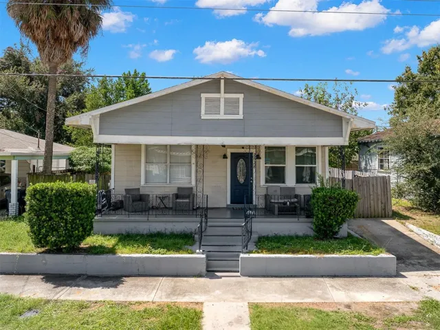 A broad covered front porch spans the front of this classic 1940 bungalow, adding architectural character and a welcoming outdoor space, while mature landscaping and a side driveway frame the home’s street presence.