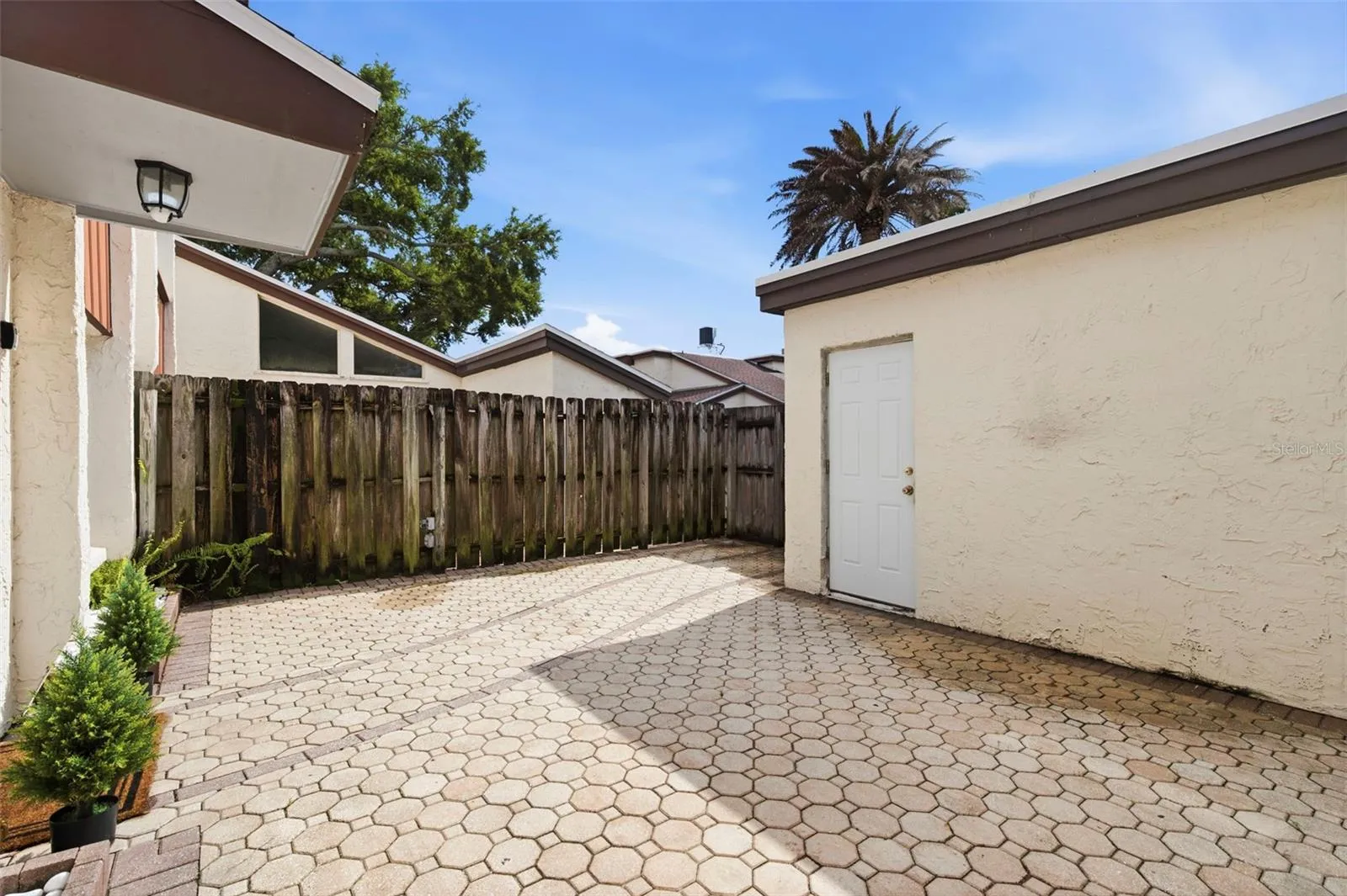 Extra large, fenced, paver patio in the front. Door to the right leads to the garage.