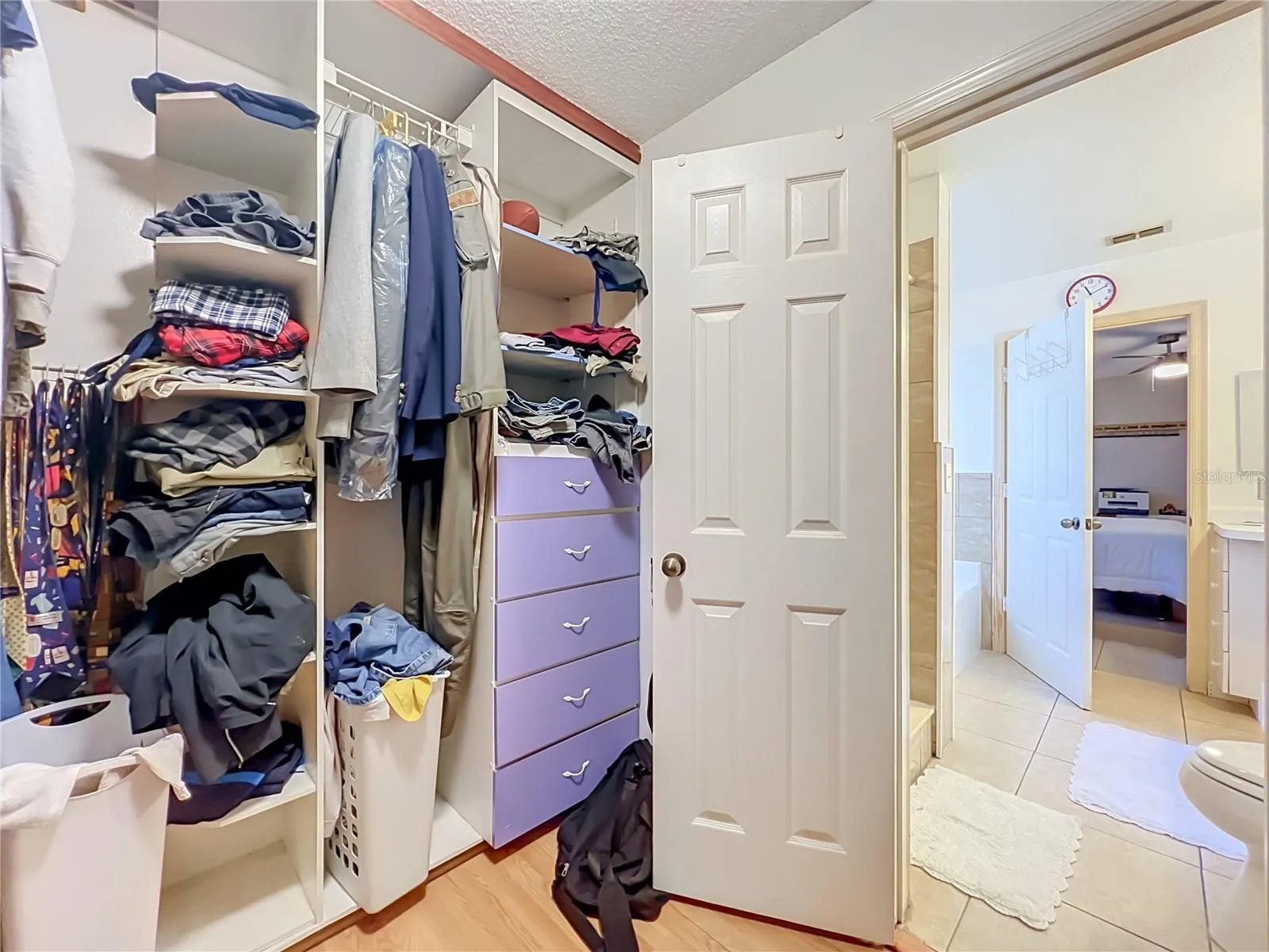Wood floors and built in drawers and shelving in the large Primary walk in closet