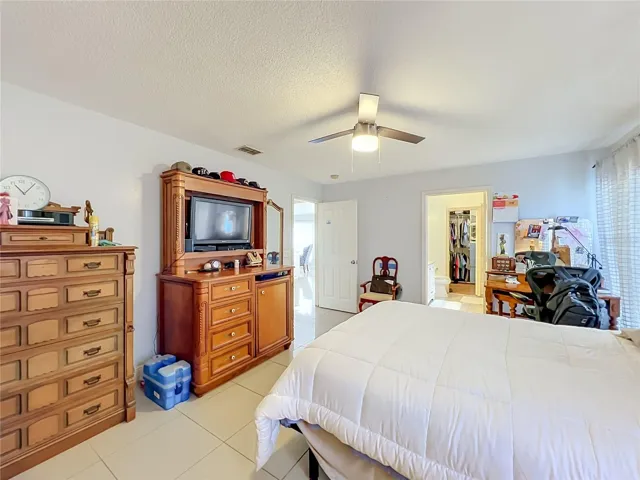 Primary bedroom on 1st floor with ceiling fan and ceramic tile floor