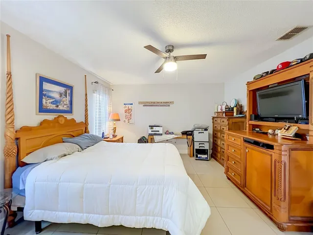 Primary bedroom on 1st floor with ceiling fan and ceramic tile floor