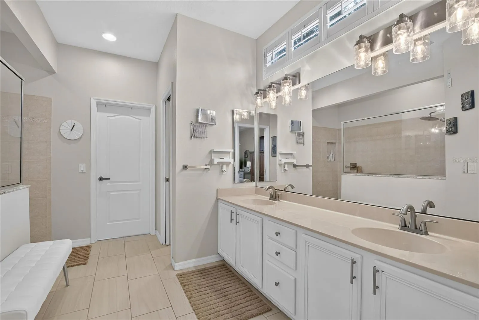 Spacious primary bath with dual-sink vanity and walk-in closet featuring additional under-stair storage