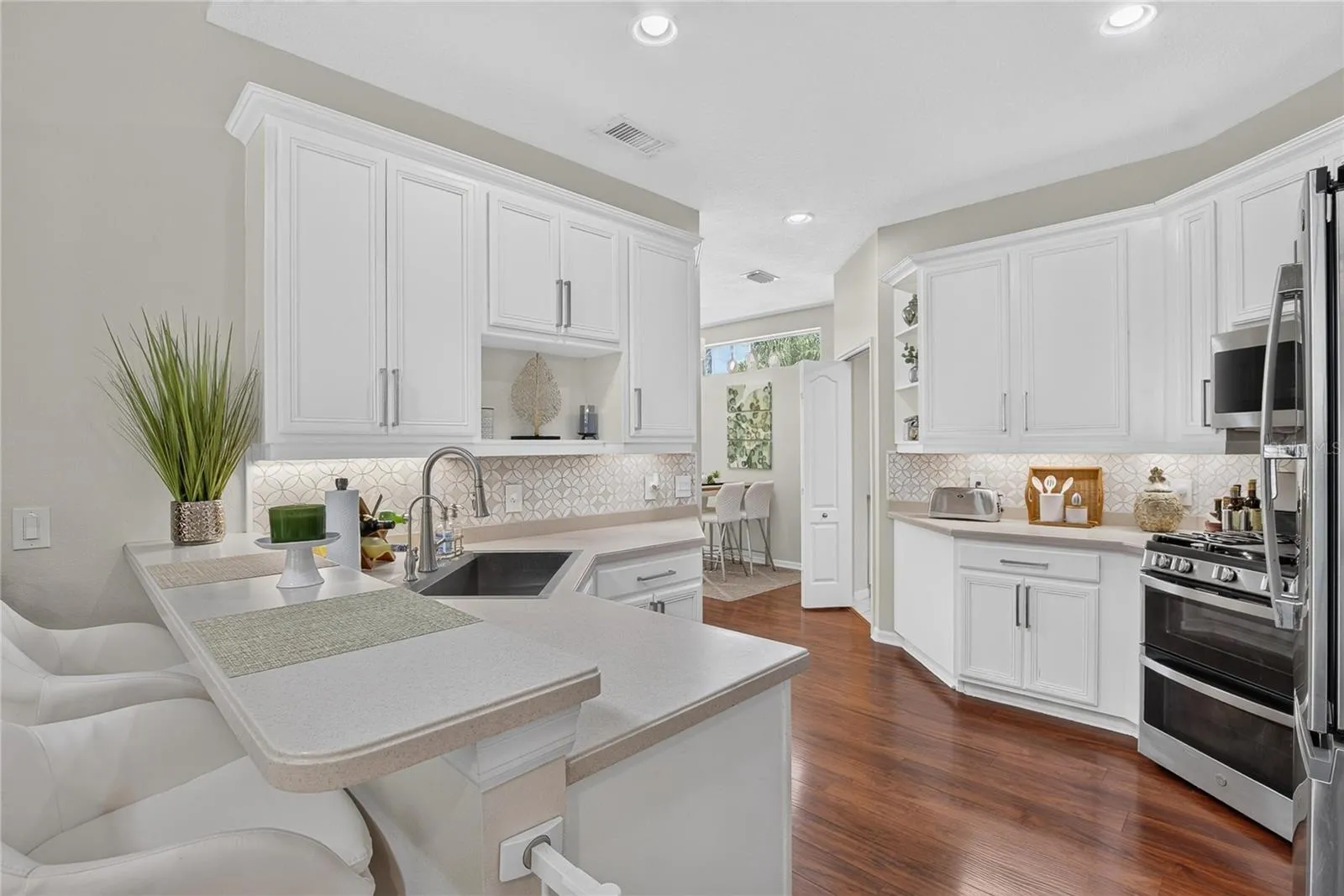 Bright kitchen with white cabinetry, stainless appliances, breakfast bar and abundant counter space.