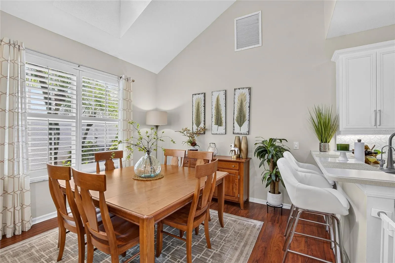 Bright dining area with soaring ceilings and plantation shutters.