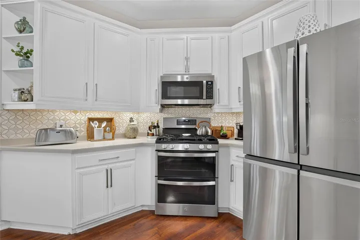 Bright kitchen with breakfast bar, abundant cabinetry, generous counter space, gas range and newer stainless steel appliances.