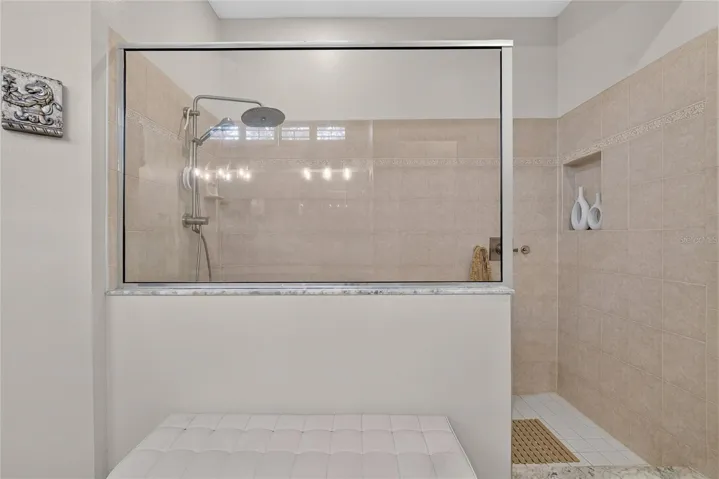 Oversized walk-in shower with tiled surround, built-in niche and multiple shower heads