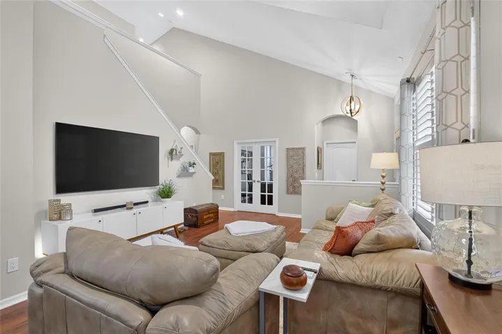 Spacious living area with soaring ceilings, abundant natural light and French doors leading to the private den.