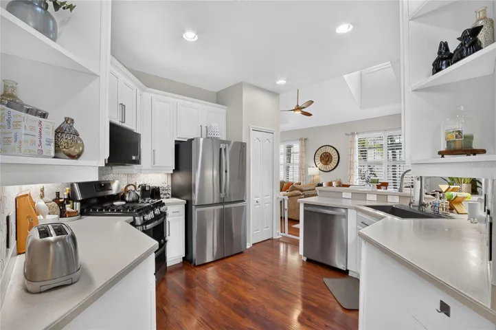 Open kitchen design with stainless steel appliances, abundant cabinetry and views into the living area.