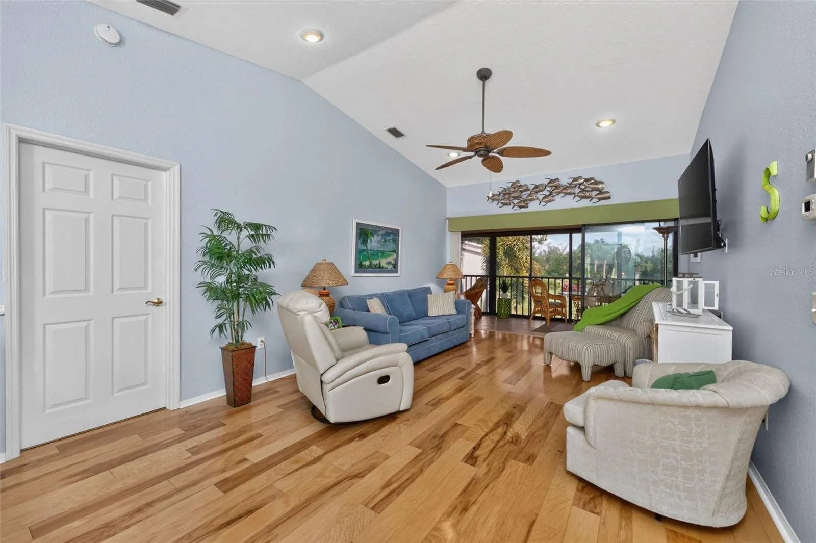 The dining/living area has a cathedral ceiling, engineered hardwood flooring and a ceiling fan.