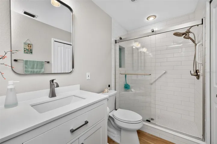 The primary bathroom features a new shower with seat and a glass door.